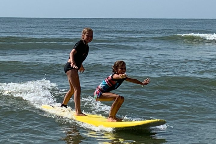 a young girl riding a wave on a surfboard in the water
