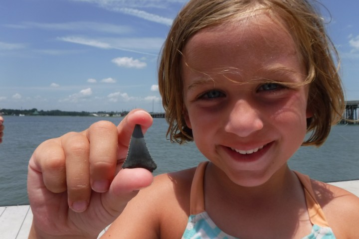 a woman smiling next to a body of water