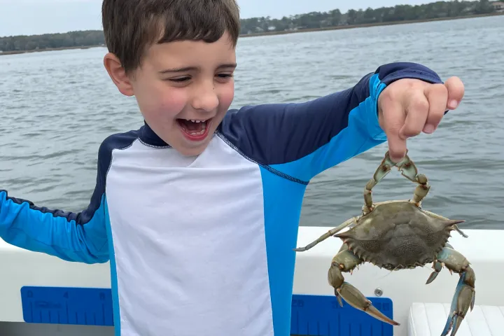 a crab with a kid standing next to a body of water