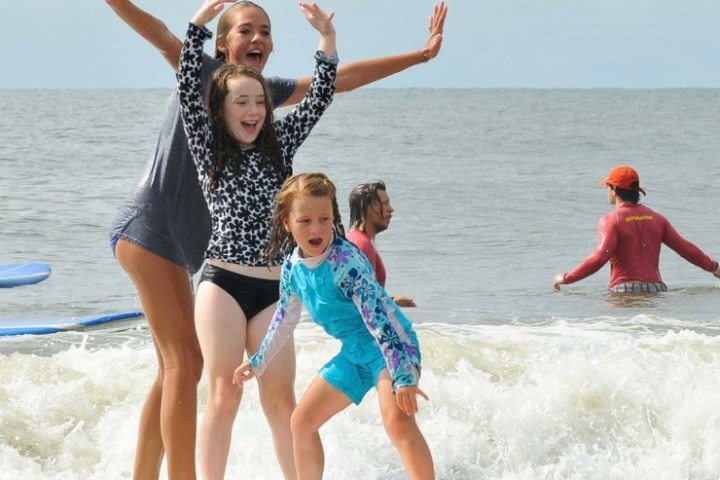 a young girl riding a wave on a surfboard in the water