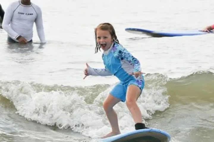 a young girl riding a wave on a surfboard in the water