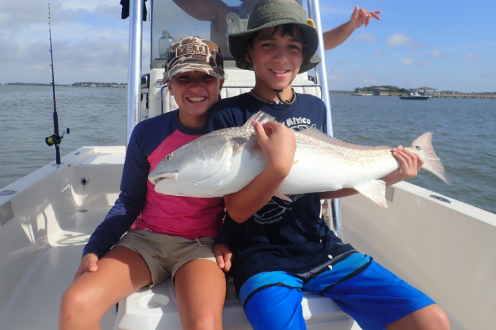 a woman holding a fish on a boat in a body of water